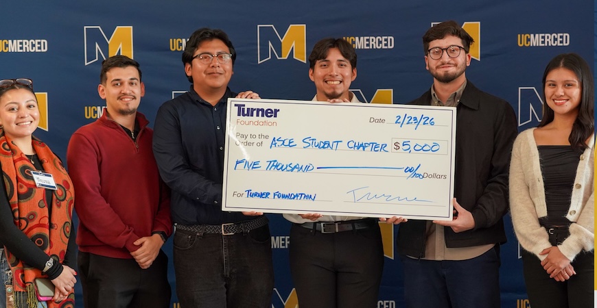 Depicted are students holding an oversized check against a blue UC Merced background.