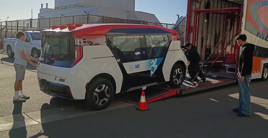 Students unload a wheelchair-accessible electric vehicle from a tractor-trailer at UC Merced. 